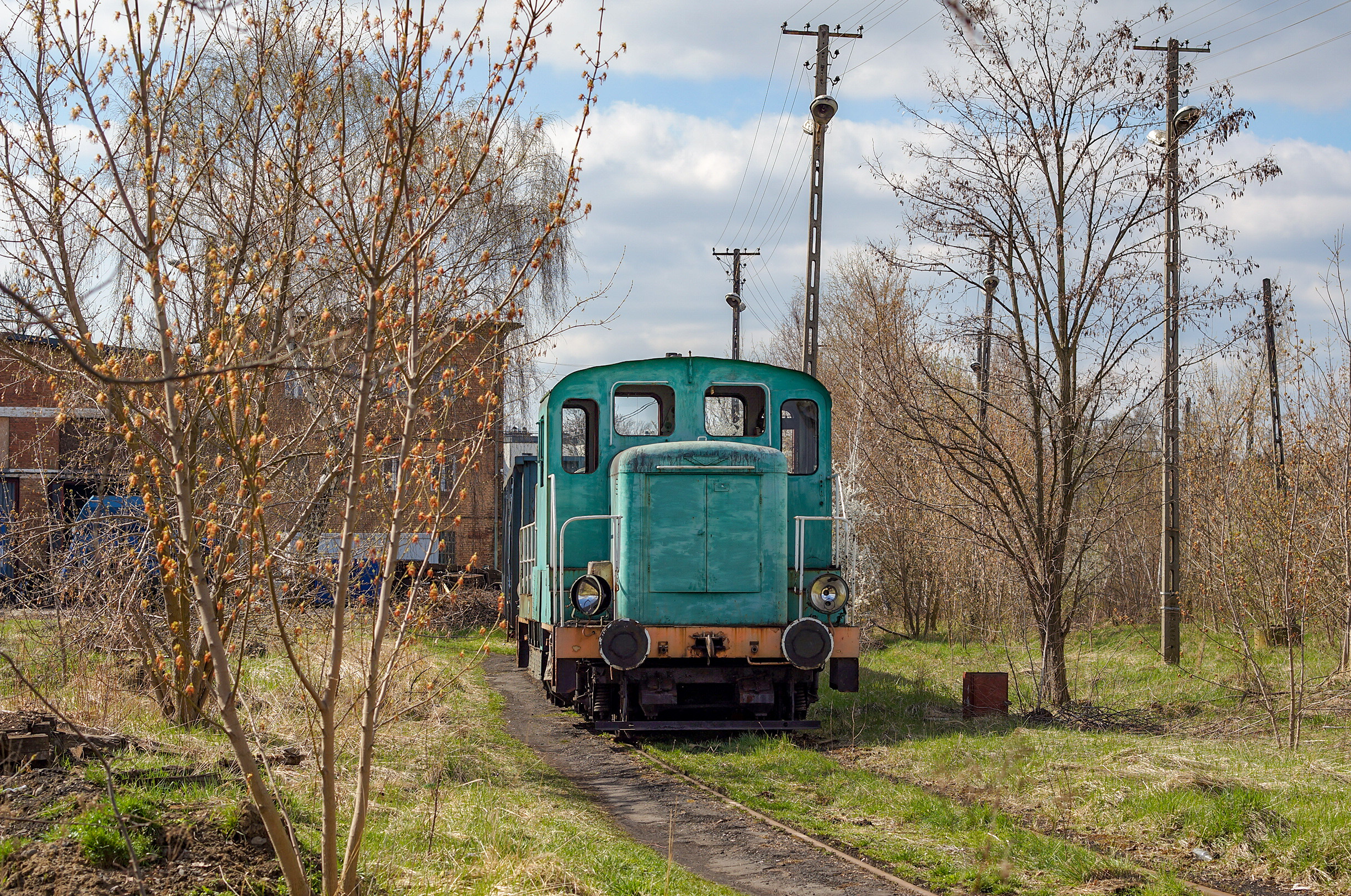 Zielony złomek pośród krzaków na terenie lokomotywowni